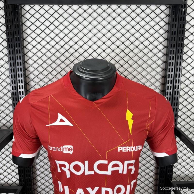 قميص اللاعب رقم 25/26 للنادي نيكاكسا (خارج أرضه) باللون الأحمر مع نقوش هندسية ذهبية على شكل صواعق