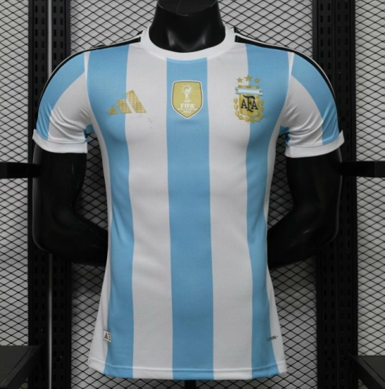 قميص المنتخب الأرجنتيني للمباريات على أرضه، إصدار اللاعب 2027، باللونين الأبيض والأزرق الفاتح مع شارة بطل كأس العالم FIFA